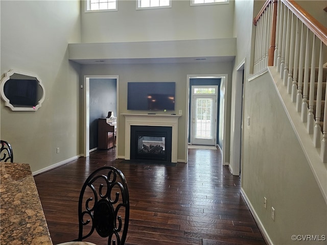 living room featuring dark hardwood / wood-style floors and a towering ceiling