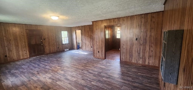 unfurnished room featuring wooden walls, a textured ceiling, and dark hardwood / wood-style flooring