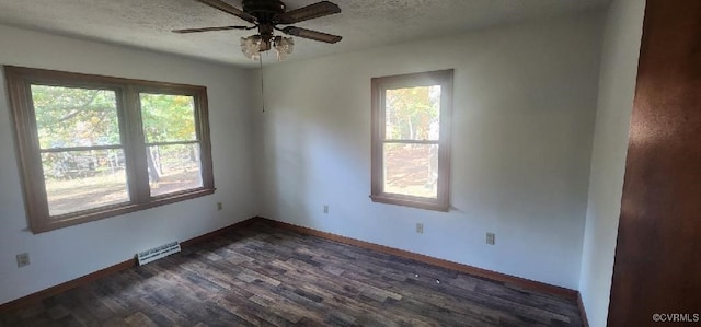 empty room with dark hardwood / wood-style floors, a healthy amount of sunlight, a textured ceiling, and ceiling fan