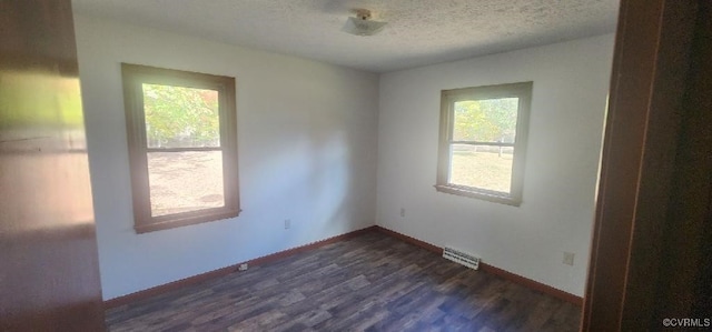 unfurnished room with a textured ceiling and dark hardwood / wood-style flooring