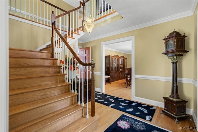 foyer entrance featuring crown molding, hardwood / wood-style flooring, and a notable chandelier