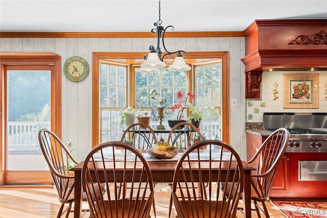 dining room featuring a notable chandelier, ornamental molding, and light wood-type flooring