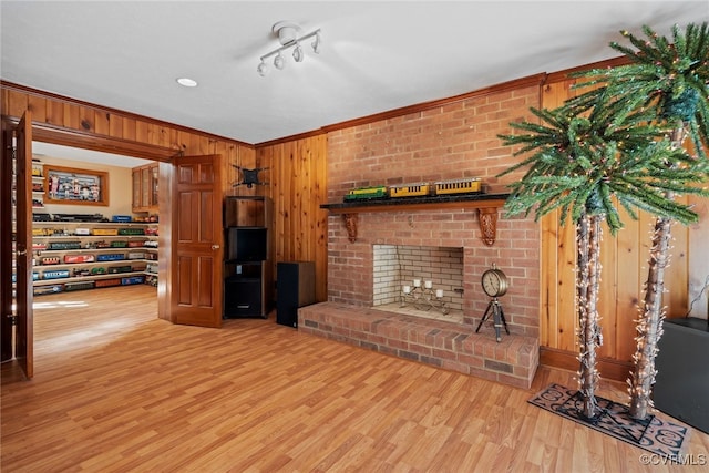 living room featuring crown molding, wood walls, wood-type flooring, and a brick fireplace