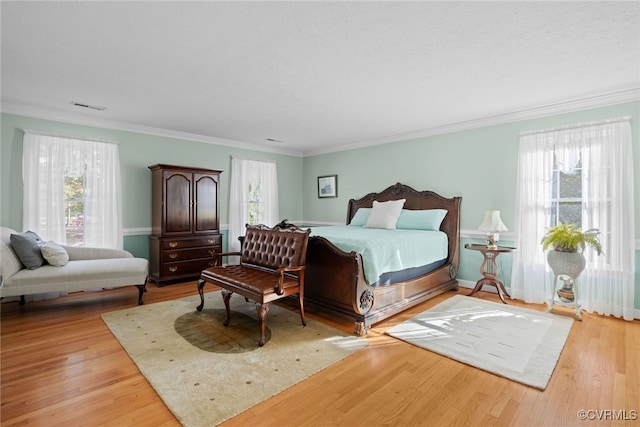 bedroom featuring crown molding, a textured ceiling, and light hardwood / wood-style floors