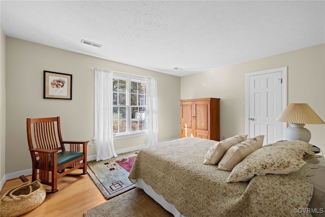 bedroom with a textured ceiling and wood-type flooring