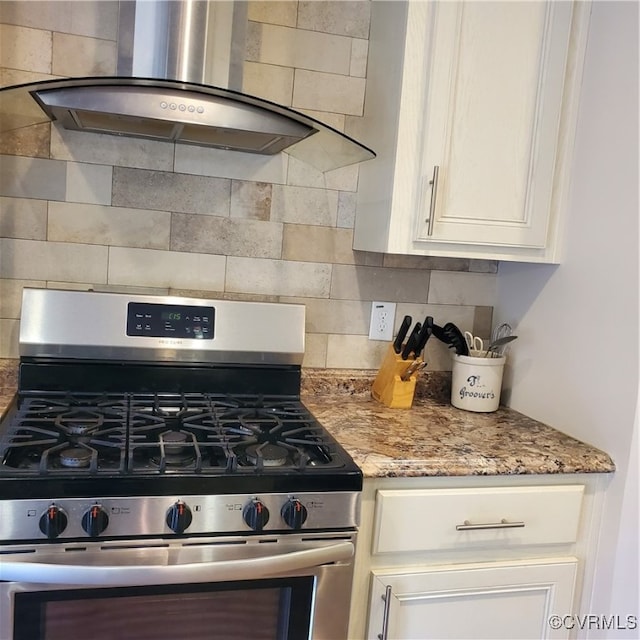 kitchen featuring stainless steel gas range oven, white cabinets, light stone counters, and exhaust hood