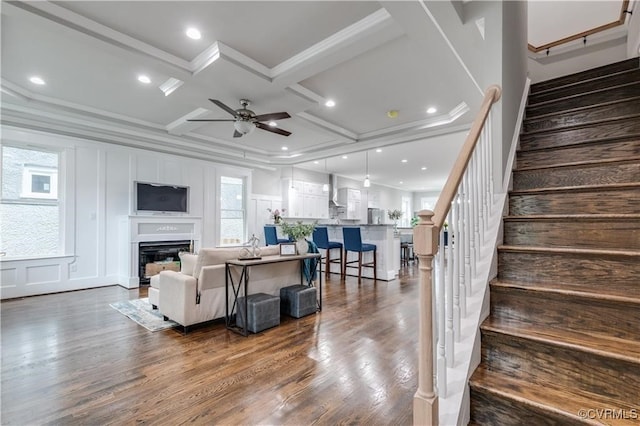 living room with dark wood-type flooring, crown molding, and coffered ceiling