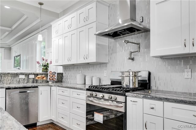 kitchen with white cabinets, hanging light fixtures, light stone counters, wall chimney exhaust hood, and stainless steel appliances