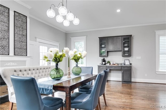 dining space featuring dark wood-type flooring, ornamental molding, and a chandelier