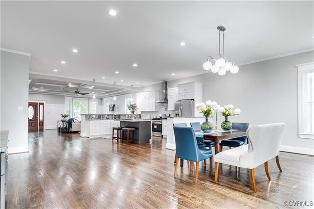 dining room with crown molding, wood-type flooring, and ceiling fan with notable chandelier