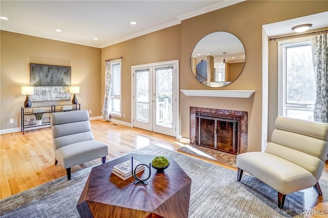 sitting room featuring a premium fireplace, plenty of natural light, crown molding, and light hardwood / wood-style flooring