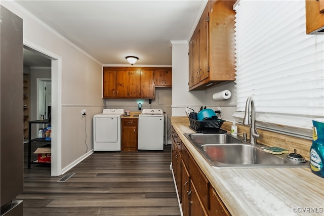 kitchen featuring ornamental molding, sink, washer and dryer, and dark hardwood / wood-style floors