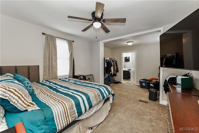 bedroom featuring a closet, a walk in closet, light colored carpet, ensuite bathroom, and ceiling fan