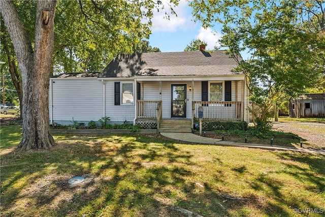 view of front of home featuring covered porch, a shed, and a front lawn