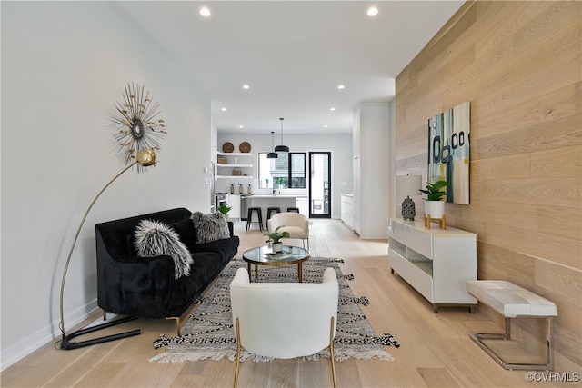 living room with wooden walls and light hardwood / wood-style flooring