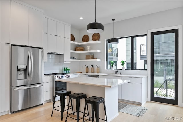 kitchen with white cabinets, light hardwood / wood-style flooring, appliances with stainless steel finishes, and a center island