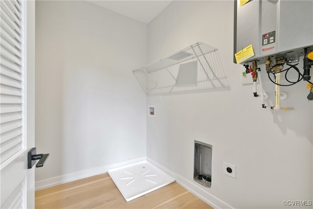 washroom featuring hardwood / wood-style floors, electric dryer hookup, hookup for a washing machine, and tankless water heater