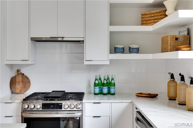 kitchen with backsplash, light stone counters, stainless steel gas range oven, and white cabinets