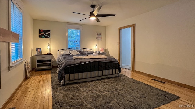 bedroom with multiple windows, hardwood / wood-style flooring, and ceiling fan