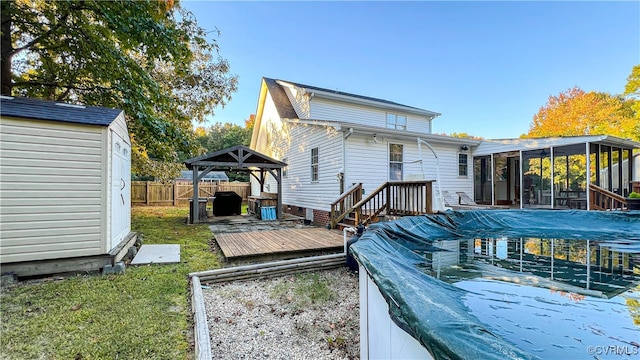 rear view of property featuring a yard, a sunroom, a gazebo, a pool side deck, and a storage shed