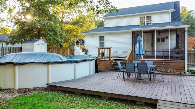 deck with a storage unit, a covered pool, and a sunroom