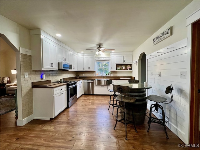 kitchen featuring ceiling fan, appliances with stainless steel finishes, hardwood / wood-style floors, and white cabinets