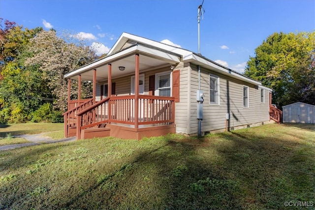 view of front of house with a front yard, a storage shed, and covered porch