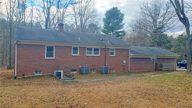 rear view of house featuring central AC and a yard