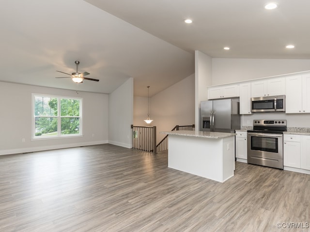 kitchen with lofted ceiling, a center island, pendant lighting, white cabinetry, and appliances with stainless steel finishes