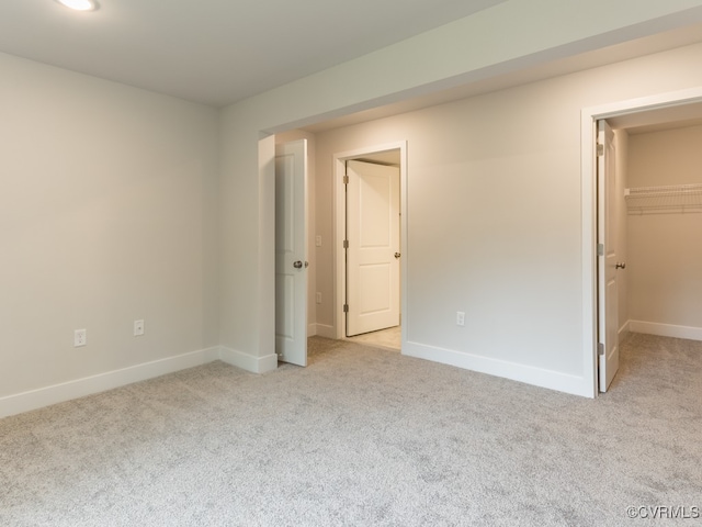 unfurnished bedroom with a spacious closet, light carpet, and a closet