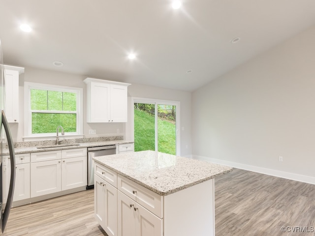 kitchen with light hardwood / wood-style flooring, sink, a center island, stainless steel dishwasher, and white cabinetry