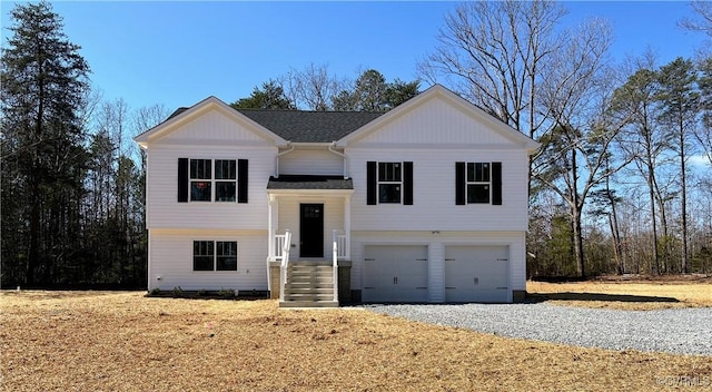 raised ranch with a garage and roof with shingles