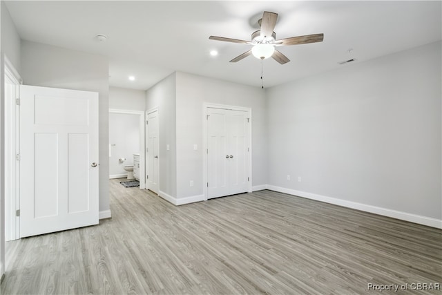 unfurnished bedroom with ensuite bathroom, light wood-type flooring, and ceiling fan