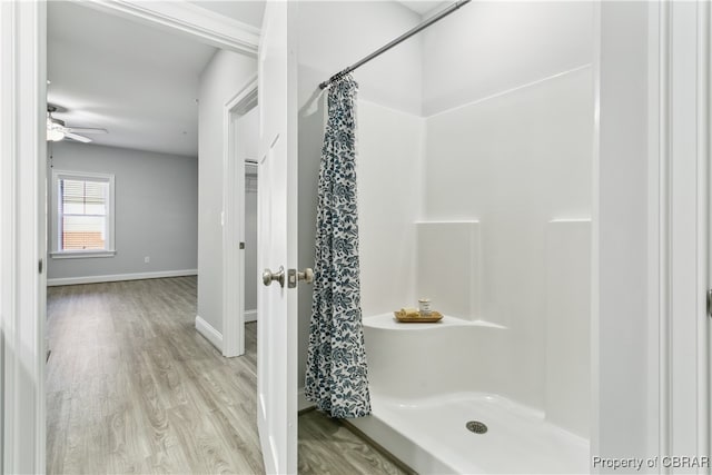 bathroom with hardwood / wood-style floors, a shower with curtain, and ceiling fan