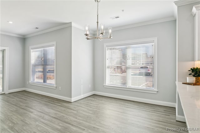 unfurnished dining area featuring an inviting chandelier, crown molding, and light hardwood / wood-style floors