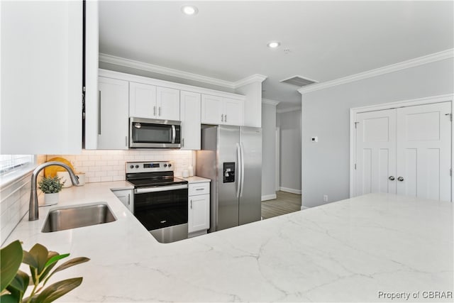 kitchen with ornamental molding, sink, white cabinets, appliances with stainless steel finishes, and light stone counters