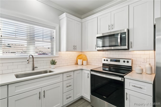 kitchen featuring sink, decorative backsplash, white cabinetry, stainless steel appliances, and ornamental molding