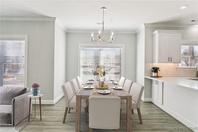 dining space with ornamental molding, a chandelier, and light hardwood / wood-style flooring