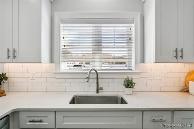 kitchen featuring a wealth of natural light, sink, and light stone countertops