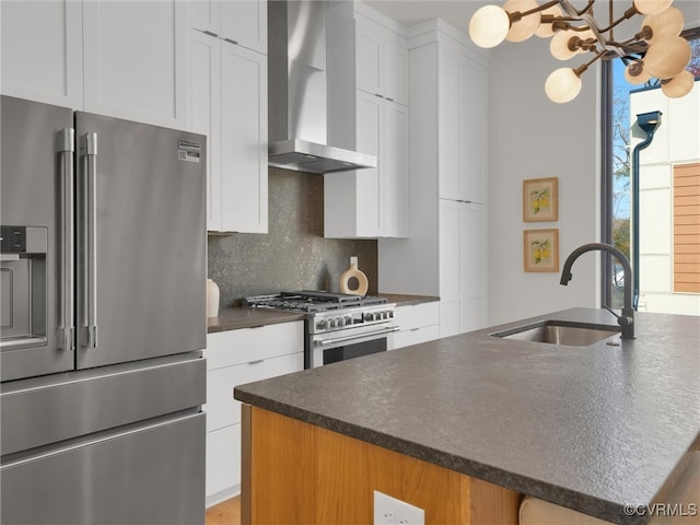 kitchen with sink, stainless steel appliances, wall chimney range hood, a center island with sink, and white cabinets