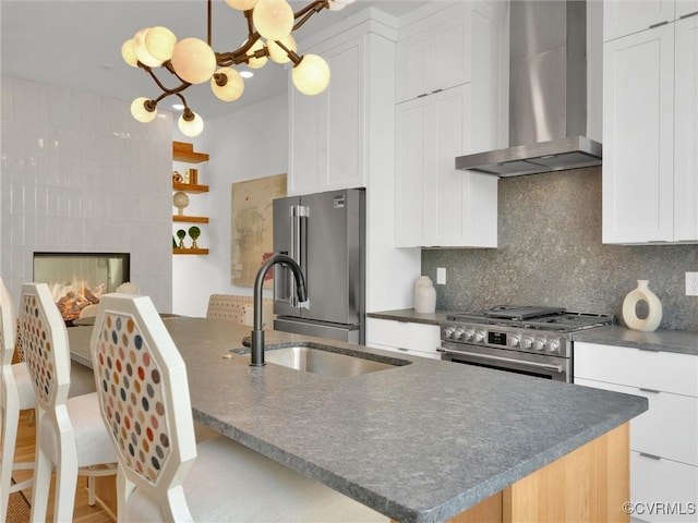 kitchen featuring sink, wall chimney range hood, premium appliances, backsplash, and white cabinets