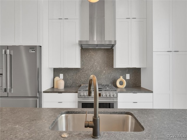 kitchen with white cabinets, high quality appliances, wall chimney range hood, and tasteful backsplash