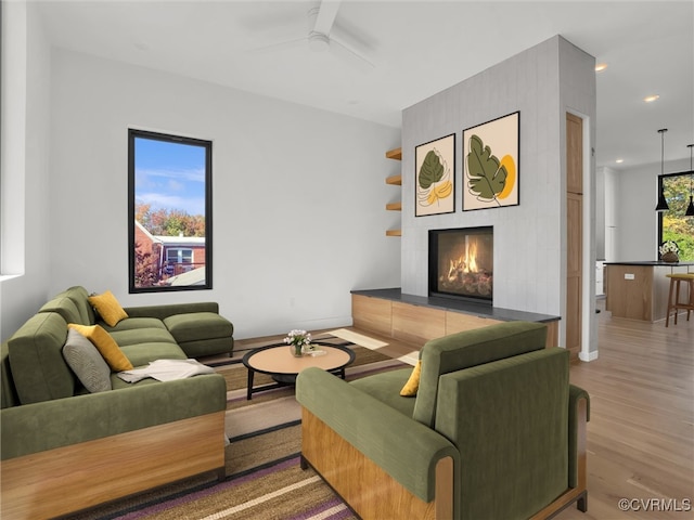 living room with ceiling fan, wood-type flooring, and a fireplace