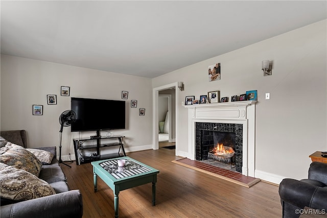 living room with a tiled fireplace and dark hardwood / wood-style flooring