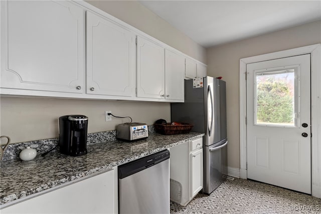 kitchen featuring dark stone countertops, white cabinetry, and stainless steel appliances