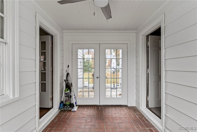 doorway with ceiling fan, wood walls, crown molding, and french doors