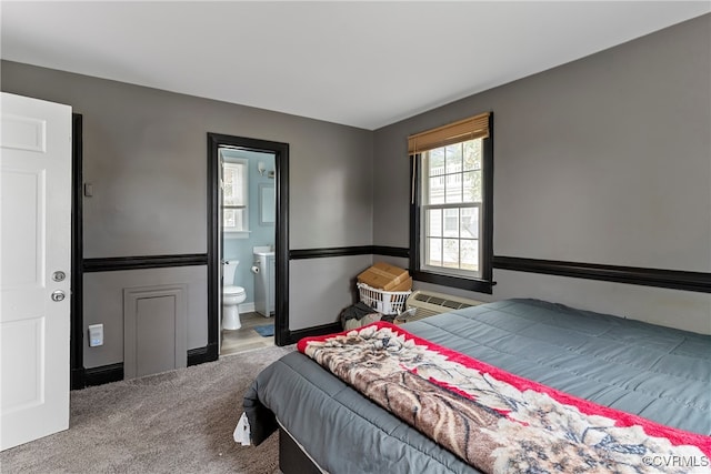 carpeted bedroom featuring a wall unit AC and ensuite bath