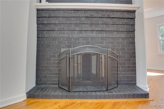 room details featuring a brick fireplace and wood-type flooring