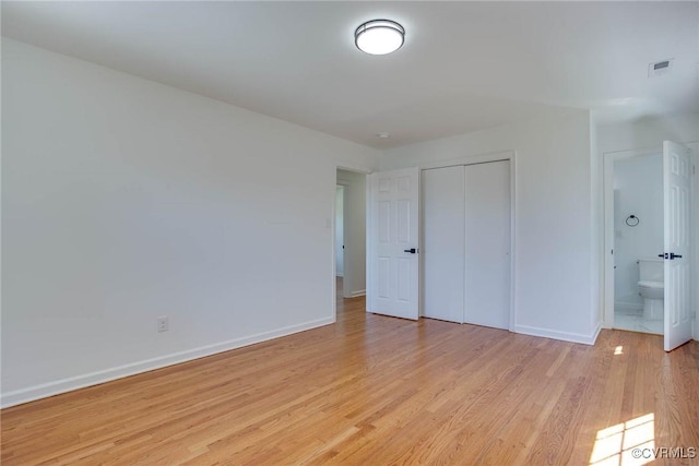 unfurnished bedroom with light wood-type flooring, a closet, and connected bathroom