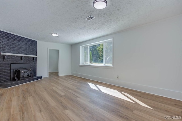 unfurnished living room featuring a textured ceiling, light hardwood / wood-style floors, and a wood stove